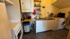 A compact kitchen with a washing machine, a sink, and a stove. - Duplex with Terrace and Private Beach Access, Garage Included (Évian-les-Bains)