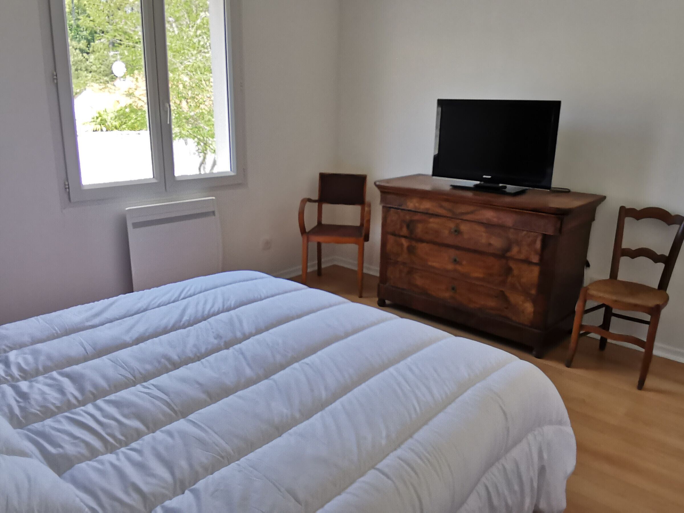 Ein Schlafzimmer mit einem Bett, einem Schminktisch, einem Fernseher und zwei Stühlen.