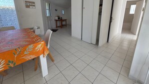A dining area with a table and chairs, a kitchen area with a microwave, and a sliding door leading to another room. - House near beach and downtown La Faute-sur-Mer (La Faute-sur-Mer)