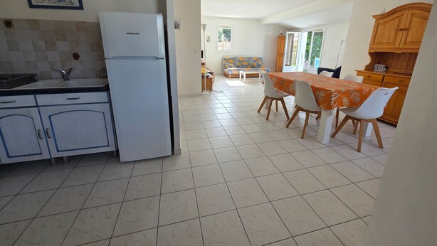 A kitchen with a refrigerator, a dining area with a table and chairs, and a sofa in the background. - House near beach and downtown La Faute-sur-Mer (La Faute-sur-Mer)