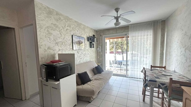 A compact living space with a kitchenette, a sofa, a dining table, and a ceiling fan. - Cozy city-center apartment, 400m from beaches, parking included (La Tranche-sur-Mer)