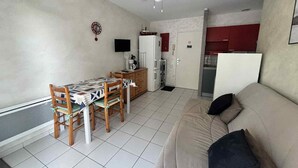 A compact living space with a dining area, kitchenette, and a sofa. - Cozy city-center apartment, 400m from beaches, parking included (La Tranche-sur-Mer)