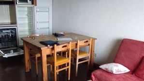 Ein kleiner, gemütlicher Raum mit einem Holztisch und Stühlen, einem roten Sofa und einem Couchtisch.