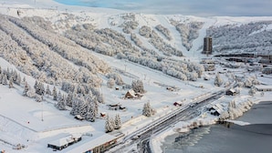 Ein schneebedecktes Skigebiet mit Gebäuden, Straßen und einem Fluss.