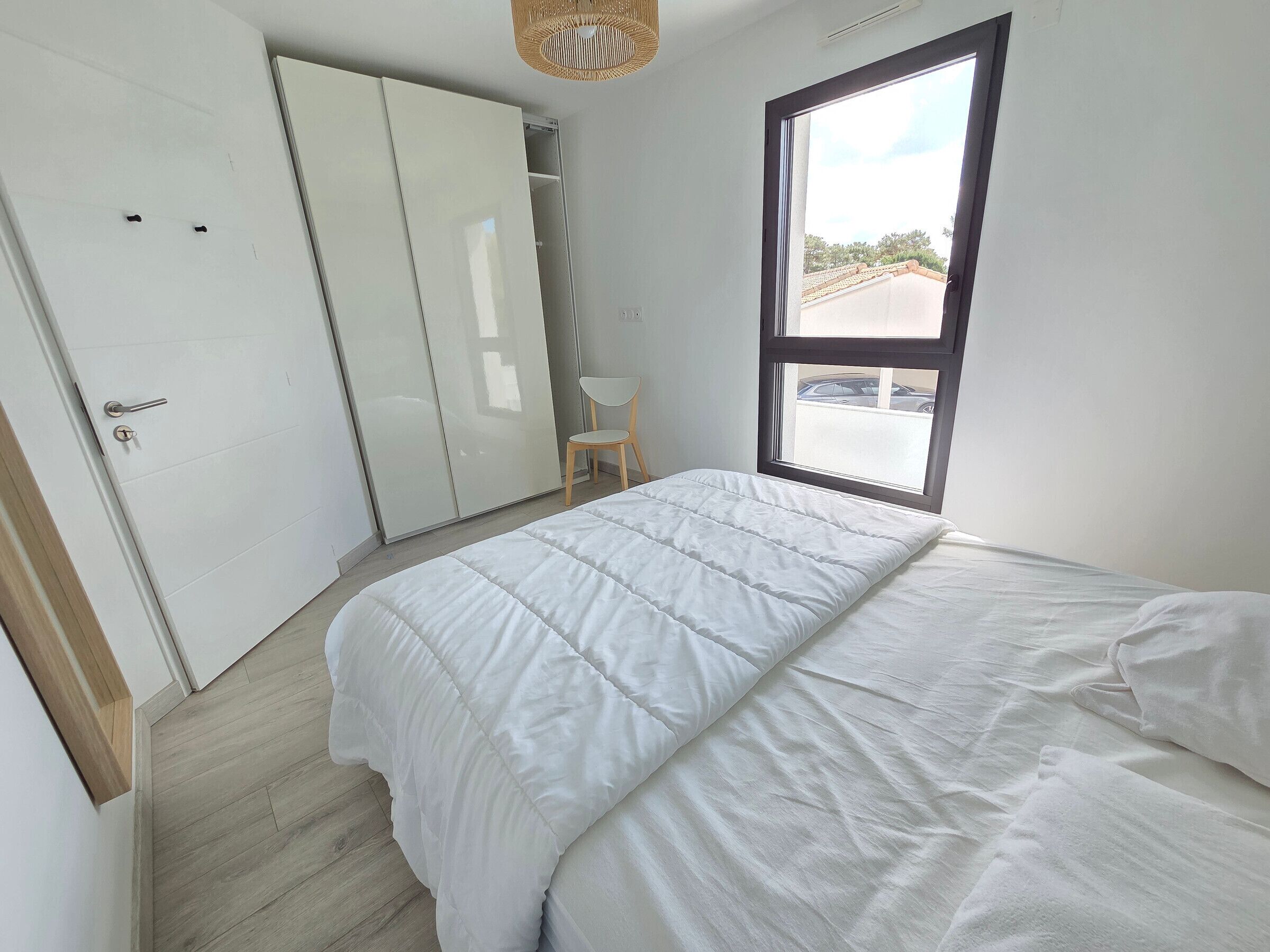 Un dormitorio con cama, armario, silla y ventana con vistas.