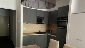A modern kitchen with grey cabinets, a wooden countertop, a microwave, an oven, and a dining table with chairs. - Studio in Gourette with pool and pets allowed, 4 pers (Gourette)