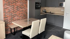 Een moderne keuken met grijze kastjes, een zwarte oven en een houten aanrecht.