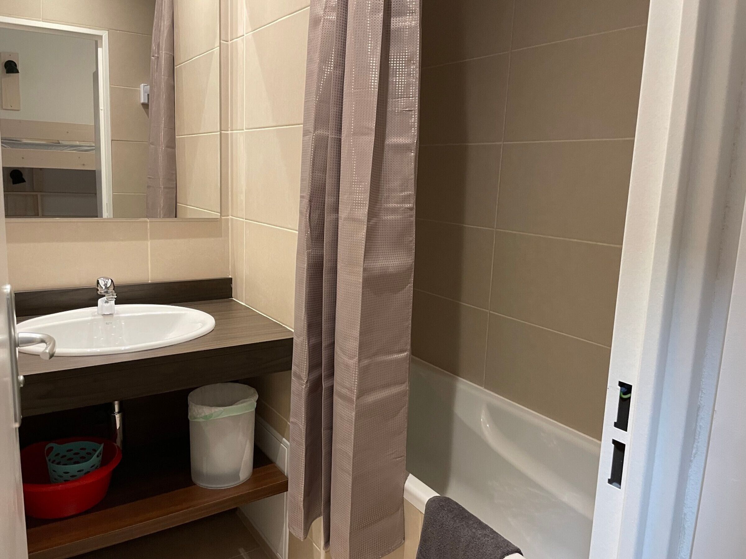 A bathroom with a white sink, a mirror, a shower curtain, and a bathtub.