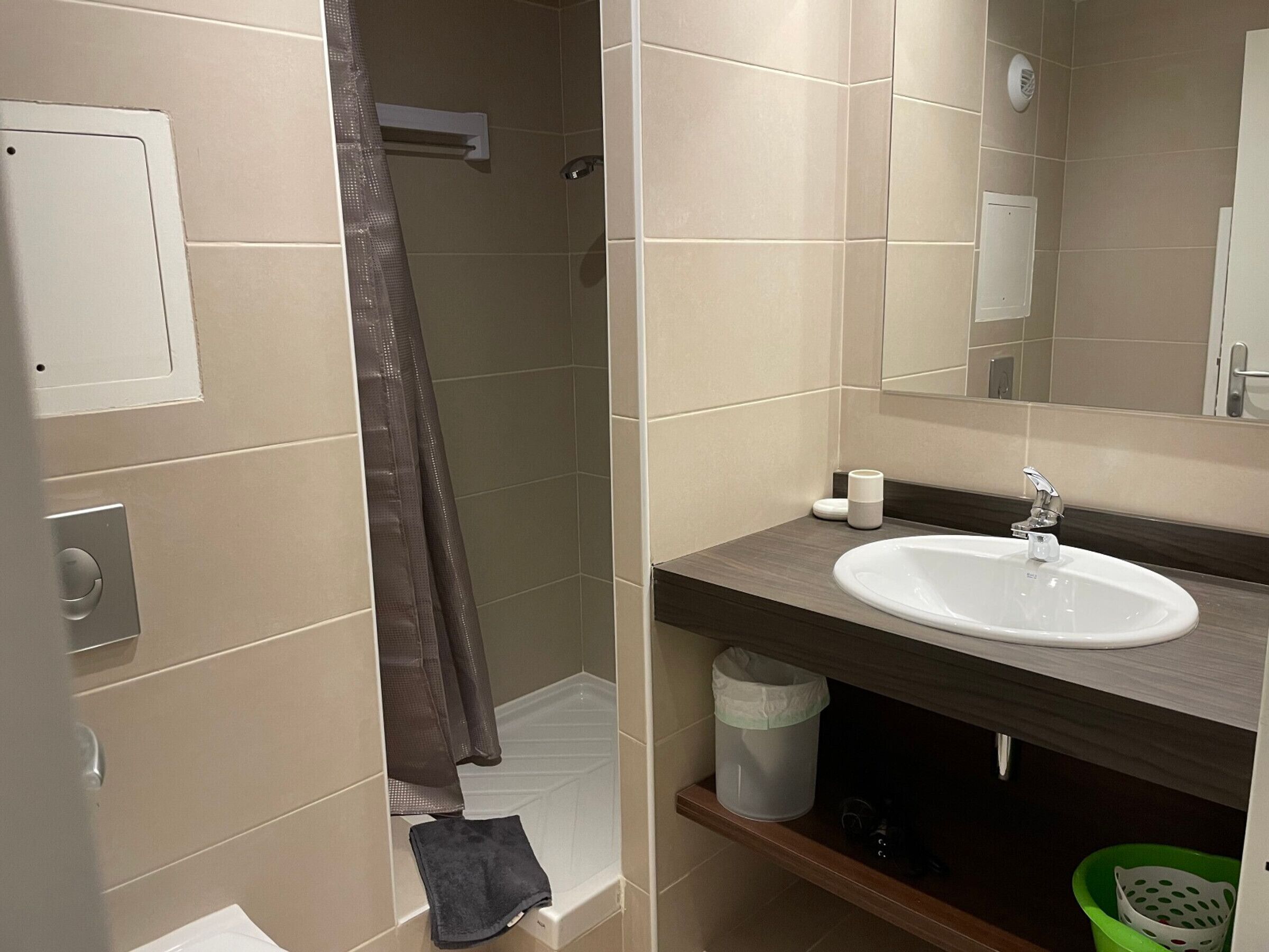 Un baño moderno con ducha, lavamanos y espejo.