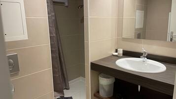 Un baño moderno con ducha, lavamanos y espejo.