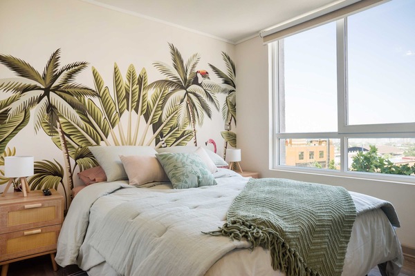 Relax in this tropical-themed bedroom with stunning city views and abundant natural light.