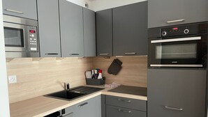 A modern kitchen with grey cabinets, a black countertop, a Bosch microwave, a JUNKER oven, and a dishwasher. - Studio for 4 in Gourette, southwest balcony, pets allowed (Gourette)