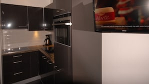A modern kitchen with dark cabinetry, a built-in oven, and a coffee maker. - Comfort studio 6 ppl, terrace, pets allowed, sheets included (Gourette)