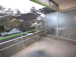 Un balcone con vista su montagne innevate e una strada con veicoli.