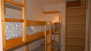 A bunk bed room with wooden bunk beds, a small shelf, and a wardrobe. - Comfortable studio 6 pers, slopes view, pets allowed (Gourette)