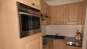 A kitchen with wooden cabinets, a stainless steel oven, a sink, and a dishwasher. - Comfortable studio 6 pers, slopes view, pets allowed (Gourette)