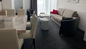 Ein modernes Hotelzimmer mit Essbereich, einer Couch und einem Bild an der Wand.