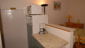 Una cucina compatta con un forno a microonde, una macchina da caffè e un piccolo pensile.