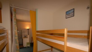 Una camera del dormitorio con letti a castello, una scrivania, una sedia, una lampada e un quadro appeso al muro.