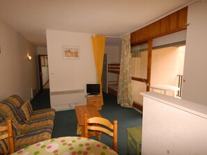 A compact room with a sofa, a small table, a TV, and a bunk bed with curtains. - Studio cabin for 6 in Gourette, pets allowed (Gourette)