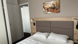 Quarto de hotel com cama, pintura, mesa de cabeceira e abajur.