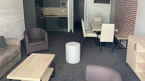 Een moderne woonkamer met een bank, een salontafel en een eethoek met stoelen en een tafel.