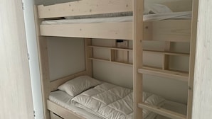 Een stapelbed met een onderbed en een bovenbed, beide met witte beddengoed.