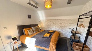 A modern bedroom with a bed, bedside table, lamp, and a hanging light fixture. - Excellent 2 bed cottage in the stunning Scottish Highlands near Portmahomack (Tain)