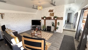 A modern living room with a stone wall, a fireplace, a sofa, a TV, and a dining area. - Excellent 2 bed cottage in the stunning Scottish Highlands near Portmahomack (Tain)