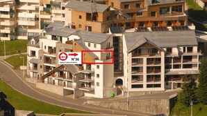 Un moderno edificio de apartamentos con varios balcones y una combinación de espacios residenciales y comerciales.