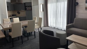 Una habitación de hotel moderna con comedor, sofá y una pequeña cocina.
