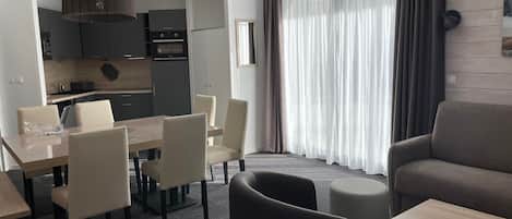 Een moderne hotelkamer met een eethoek, een bank en een kitchenette.