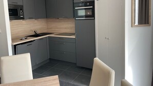 Una cocina moderna con gabinetes grises, un microondas negro y un horno empotrado. Hay una zona de comedor con una mesa y sillas.