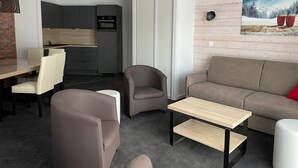 Ein modernes Wohnzimmer mit einer Couch, Sesseln, einem Couchtisch und einem Essbereich mit Stühlen und einem Tisch.