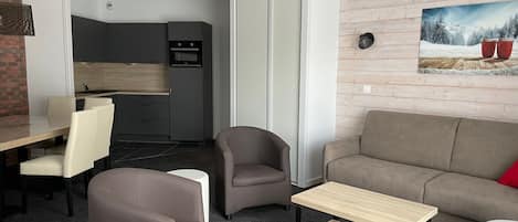 Una sala de estar moderna con un sofá, sillones, una mesa de centro y un comedor con sillas y una mesa.