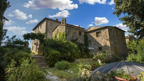 A rustic stone building with a garden in front, featuring a small staircase leading to the entrance. - Villa Storica Volterra (Volterra)