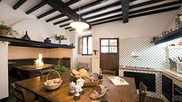 A cozy kitchen with a wooden table set for a meal, a fireplace, and a patterned backsplash.