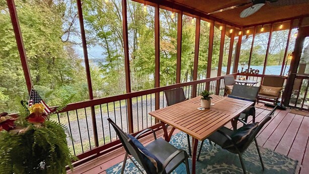 A wooden deck with a table and chairs, overlooking a lake. - Sunfish Cove – Pet-Friendly Lakeside Retreat (Scottsville)