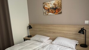 A hotel room with a wooden headboard, a bed with white bedding, two bedside lamps, and a framed picture on the wall. - Gourette: 3-room Apt, 8 pers, pool (Gourette)
