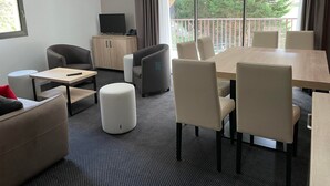 A modern hotel room with a large balcony, a TV, a wooden cabinet, and a dining area with chairs and a table. - Gourette: 3-room Apt, 8 pers, pool (Gourette)