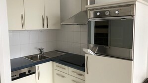 A compact kitchen with white cabinets, a stainless steel oven, and a sink. - Comfortable studio, 6 pers, mountain view, pets allowed, sheets provided (Gourette)