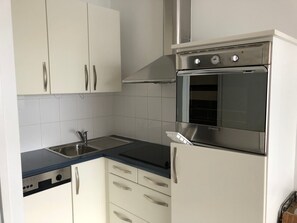 A compact kitchen with white cabinets, a stainless steel oven, and a sink. - Comfortable studio, 6 pers, mountain view, pets allowed, sheets provided (Gourette)