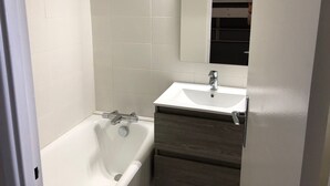 A bathroom with a white bathtub, a sink, and a mirror. - Comfortable studio, 6 pers, mountain view, pets allowed, sheets provided (Gourette)