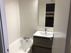 A bathroom with a white bathtub, a sink, and a mirror. - Comfortable studio, 6 pers, mountain view, pets allowed, sheets provided (Gourette)