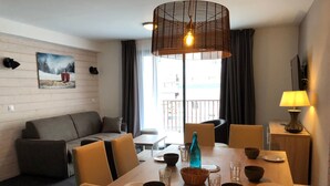 Ein modernes Wohnzimmer mit einer Couch, einem Esstisch, Stühlen und einer Pendelleuchte.