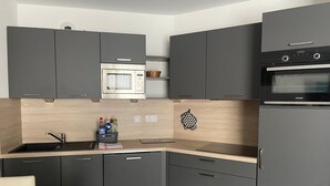 Eine moderne Küche mit grauen Schränken, einer eingebauten Mikrowelle, einem JUNKER-Backofen und einer schwarzen Küchenwand.