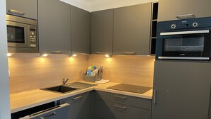 A modern kitchen with grey cabinets, a built-in microwave, a dishwasher, and a double oven. - Gourette: 66m² apt for 8, pool, pets allowed (Gourette)