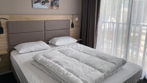 A hotel room with a large bed, a headboard, a bedside table, a lamp, a picture on the wall, and a window with curtains. - Gourette: 66m² apt for 8, pool, pets allowed (Gourette)
