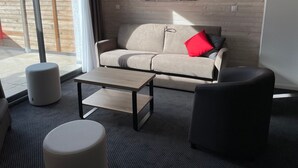 A modern living room with a beige sofa, a coffee table, and two ottomans. - Gourette: Apartment for 8, 56m², Pets Allowed (Gourette)
