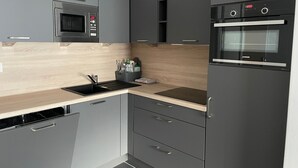 A modern kitchen with grey cabinets, a built-in microwave, a sink, and a JUNKER oven. - Studio cabin Gourette 6 ppl with pool and pets allowed (Gourette)
